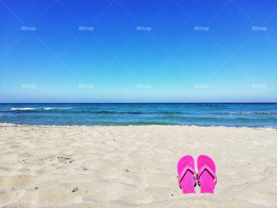 Flip flops embedded in the sea sand