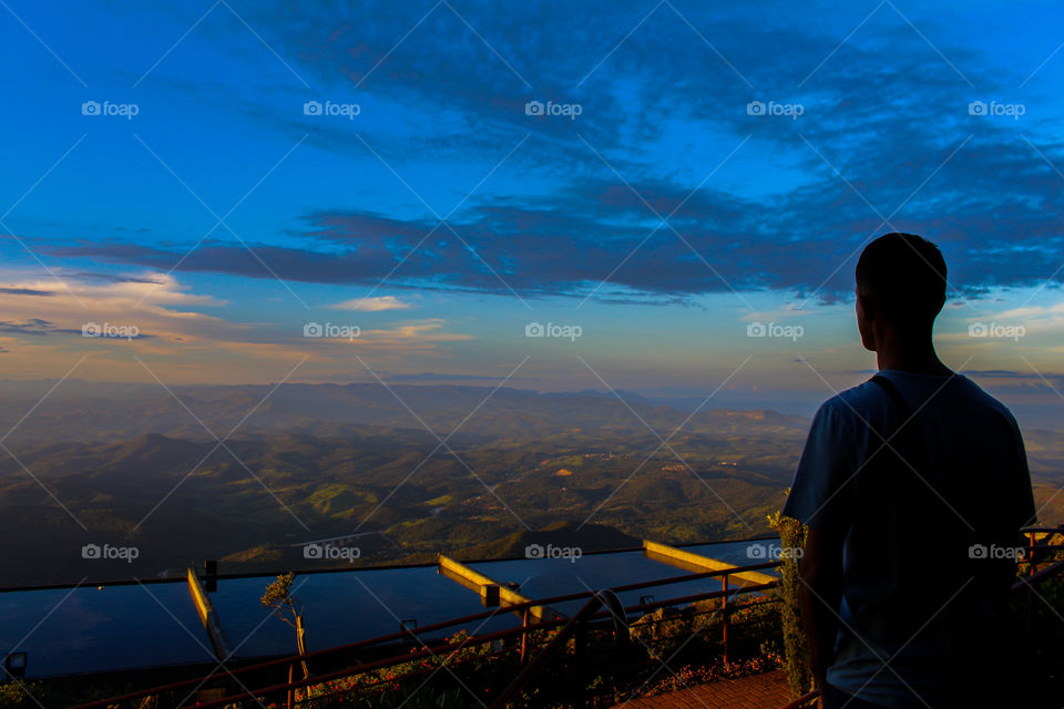 Man watching the sunset from the top of the mountain