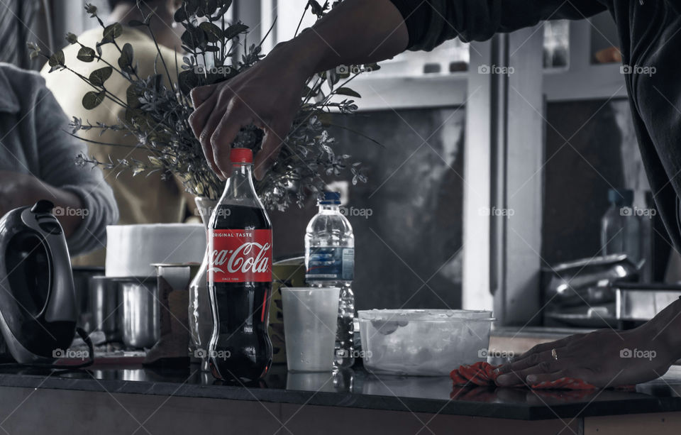 A random candid shot of a guy picking up a bottle of coca cola while cleaning the dining area