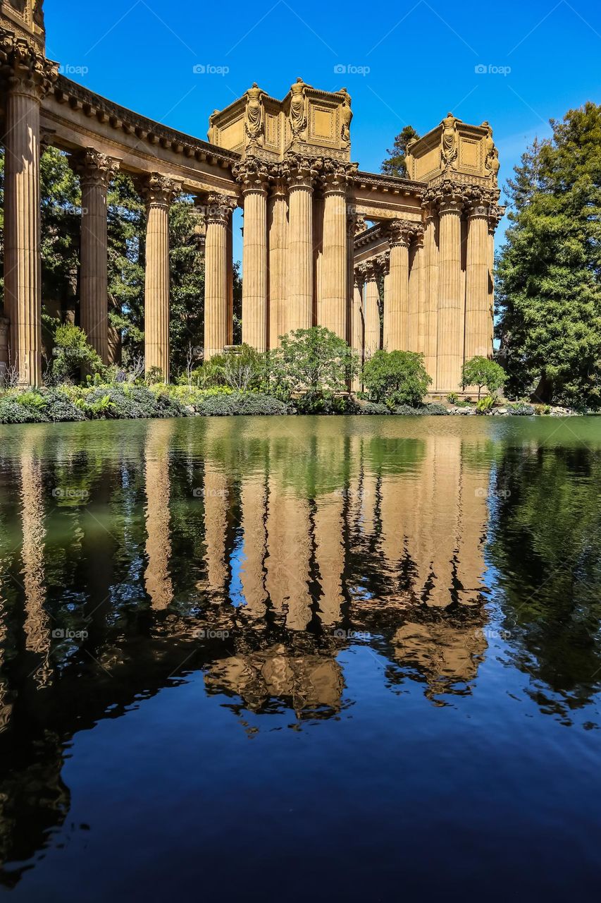 Palace of fine arts in San Francisco California on a beautiful sunny afternoon in the spring, with the Greco Roman style columns reflecting in the lagoon like a mirror