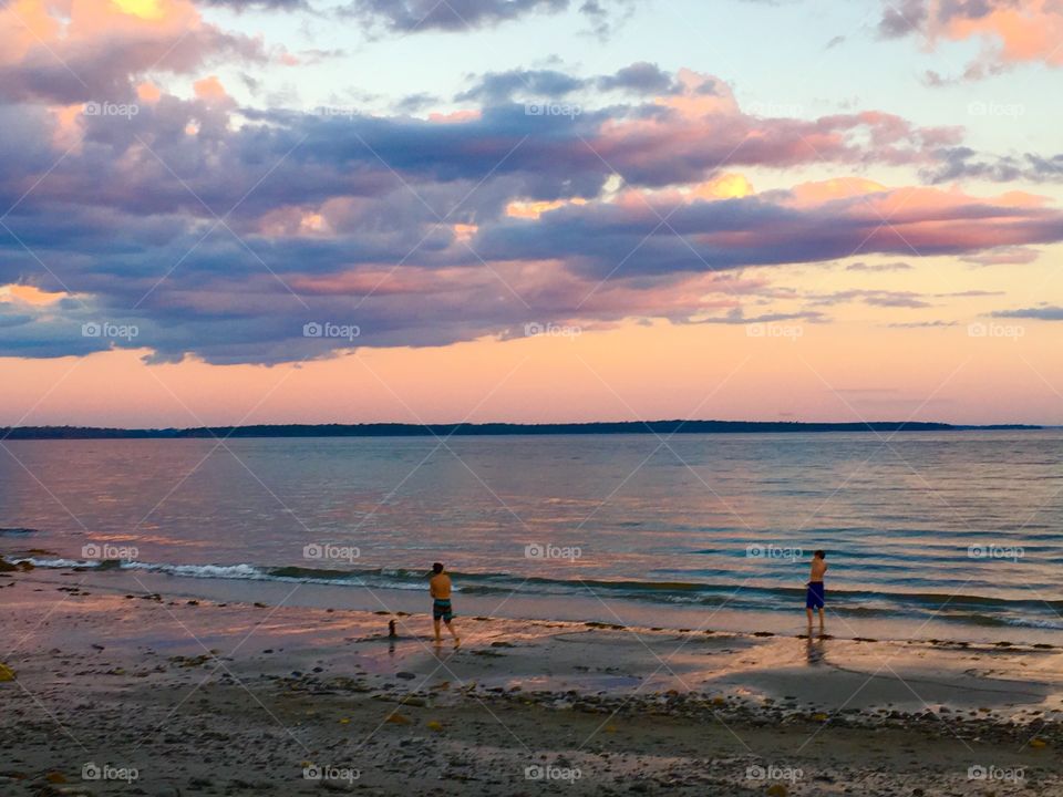 Two boys playing on shore at sunset