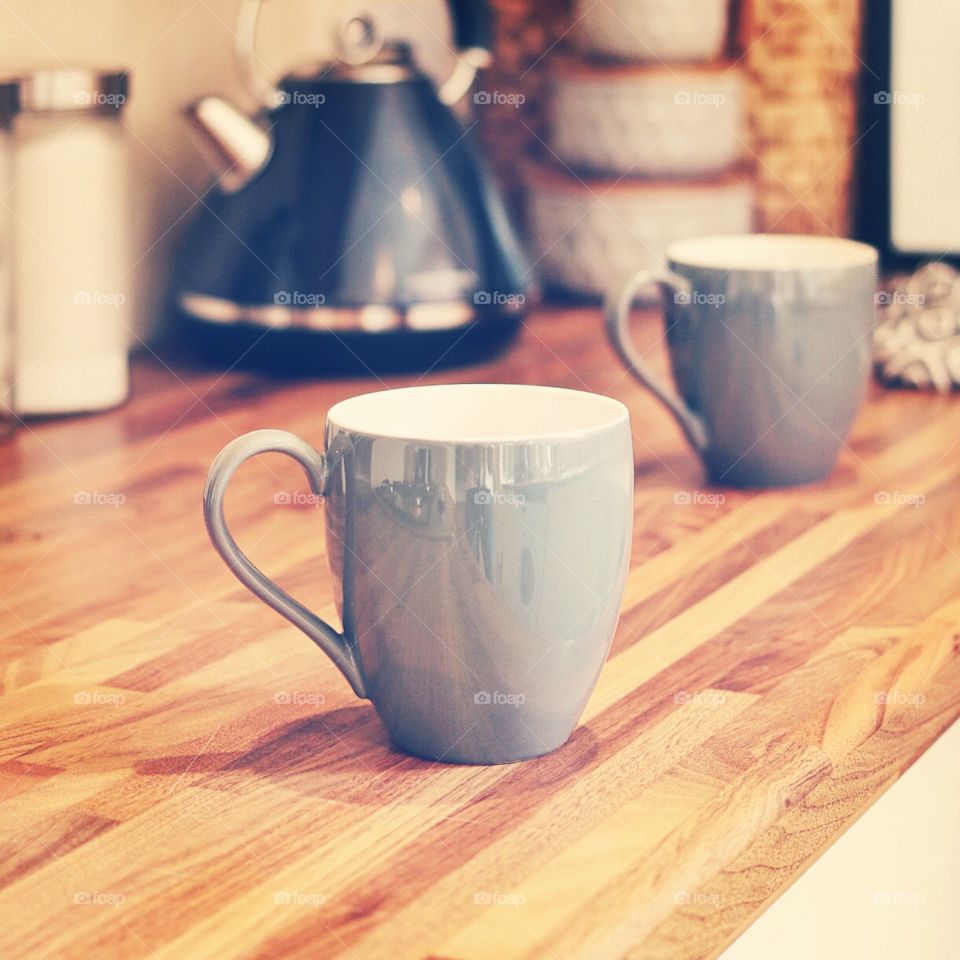 Grey mugs on wooden bench in kitchen waiting for the kettle to boil. 