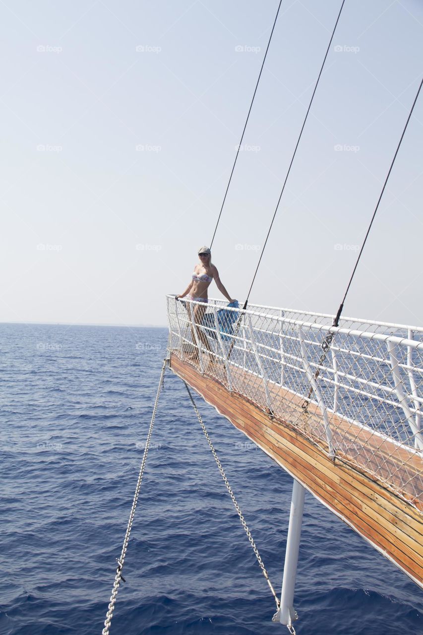 A ship sailing on the waves of the blue sea and a girl.