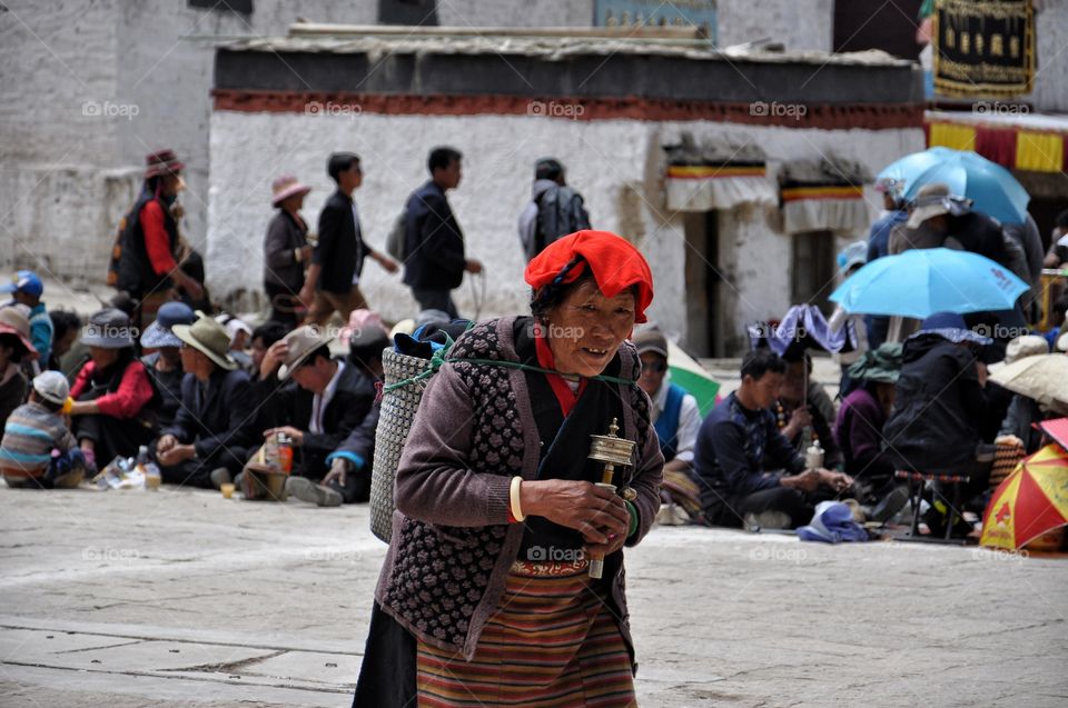 old tibetan woman in yard of buddhist monastery in tibet