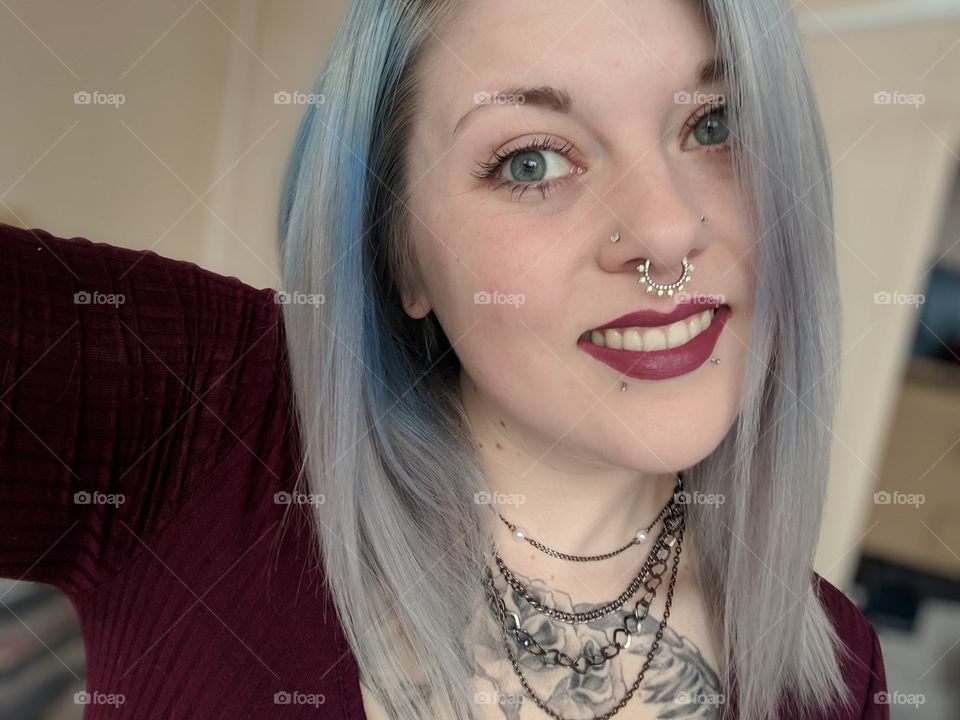 smiling alternative female with blue eyes, light hair, piercing and tattoos. minimal makeup. nyx cosmetics lip stick.