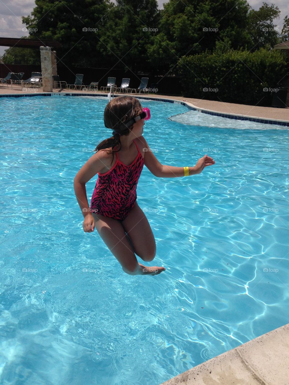 Do the twist . Girl jumping in the pool while twisting in the air