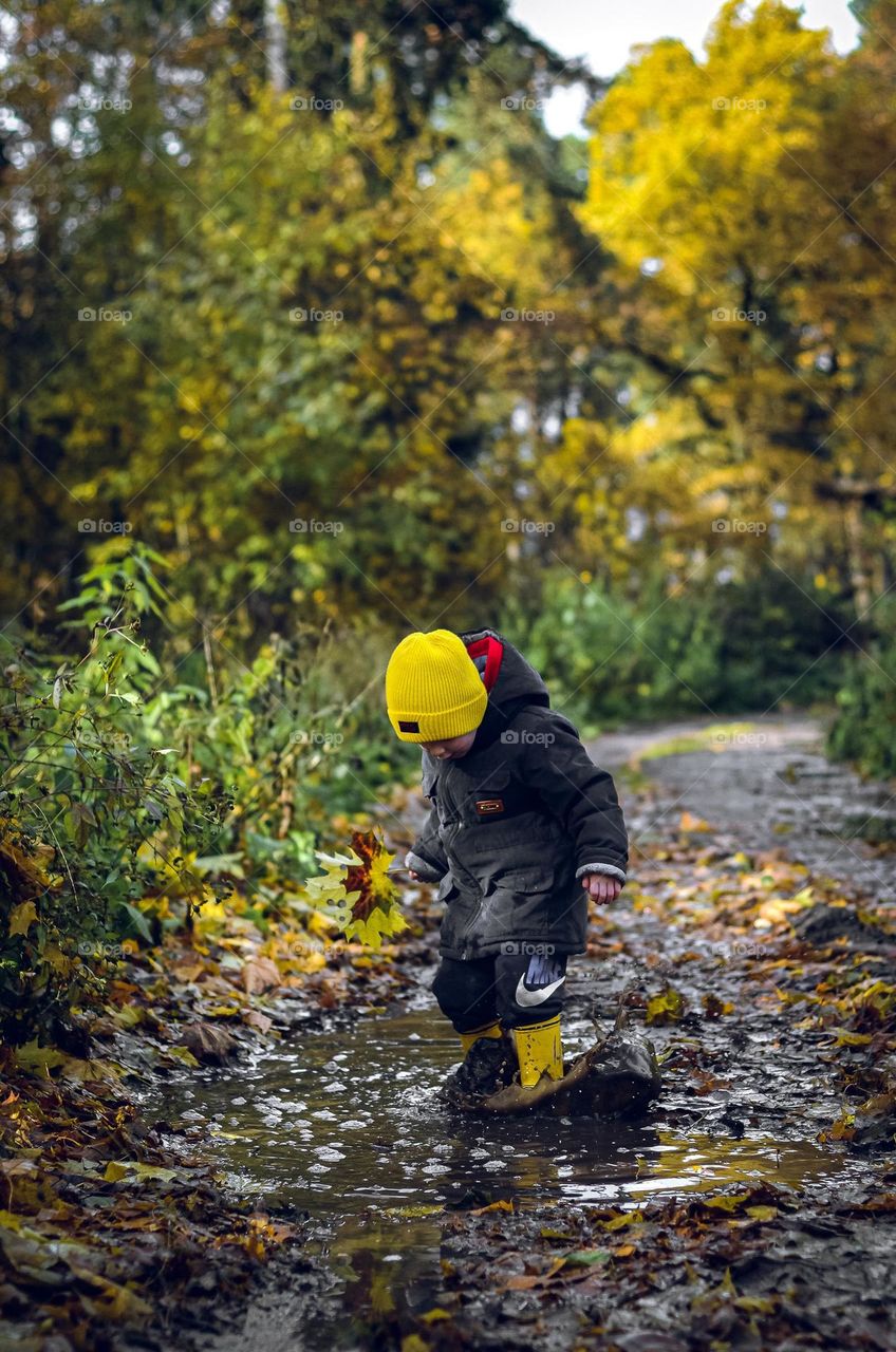 The boy is playing in the puddle.