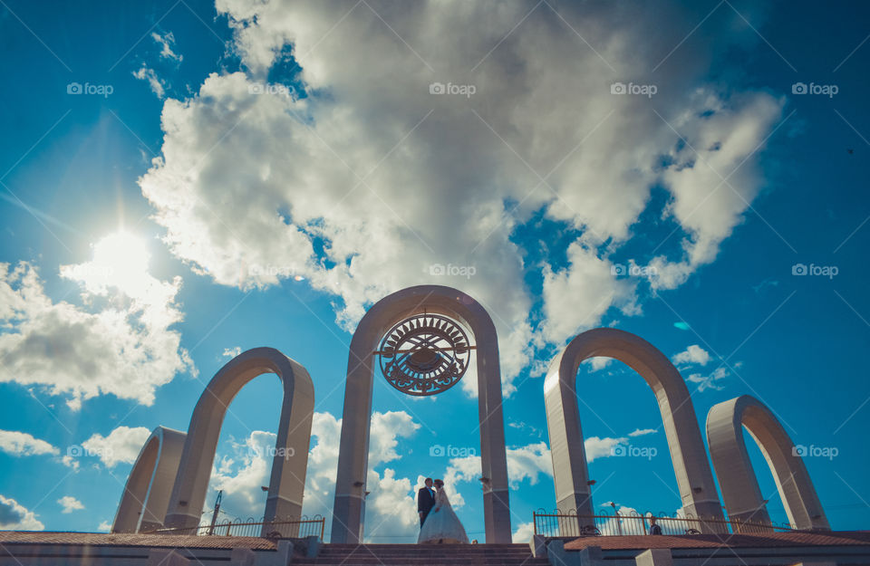 влюбленная пара жених и невеста стоят обнявшись в арке