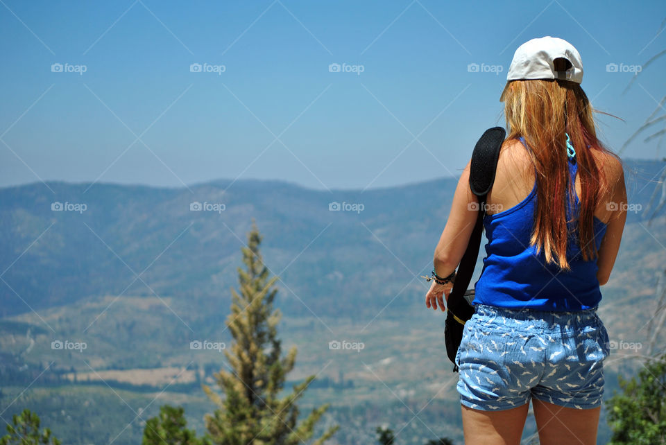 Girl facing the hiking view holding a bag of camera