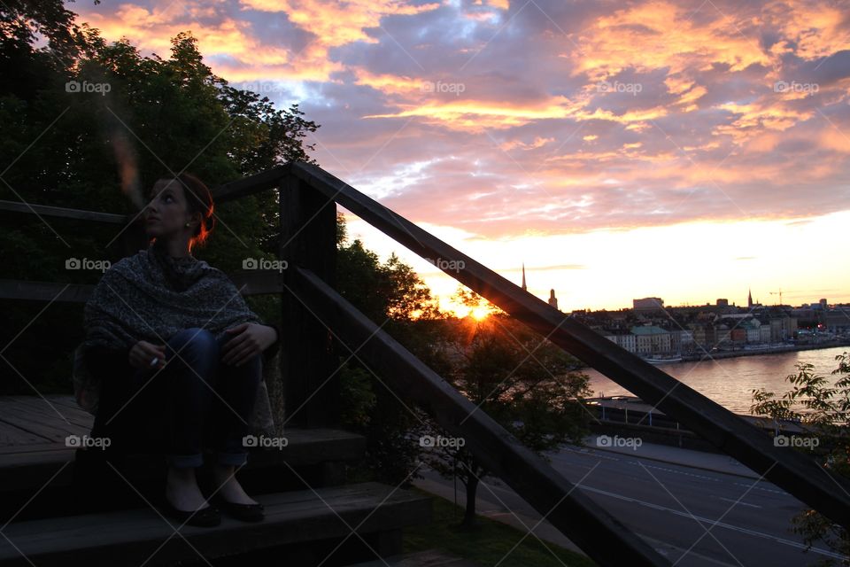 Woman smoking in sunset. Sunset over Stockholm 