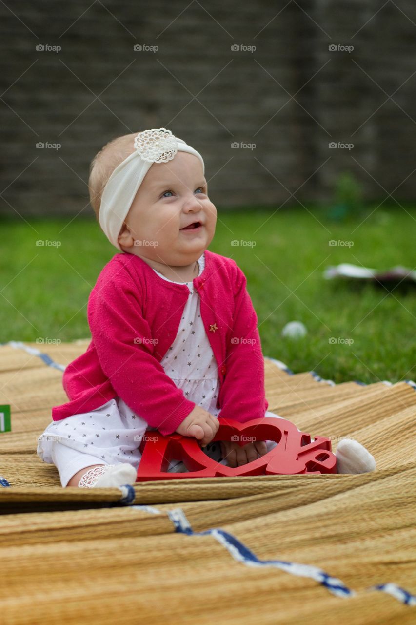 little girl. a baby sitting at a grass yard