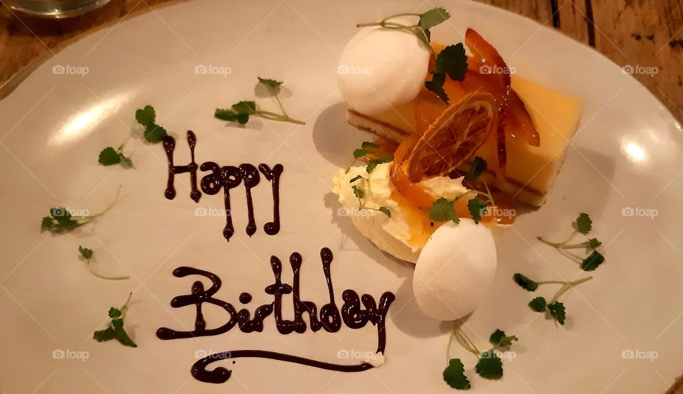 lemon and orange dessert with meringue and cream and happy birthday written in chocolate