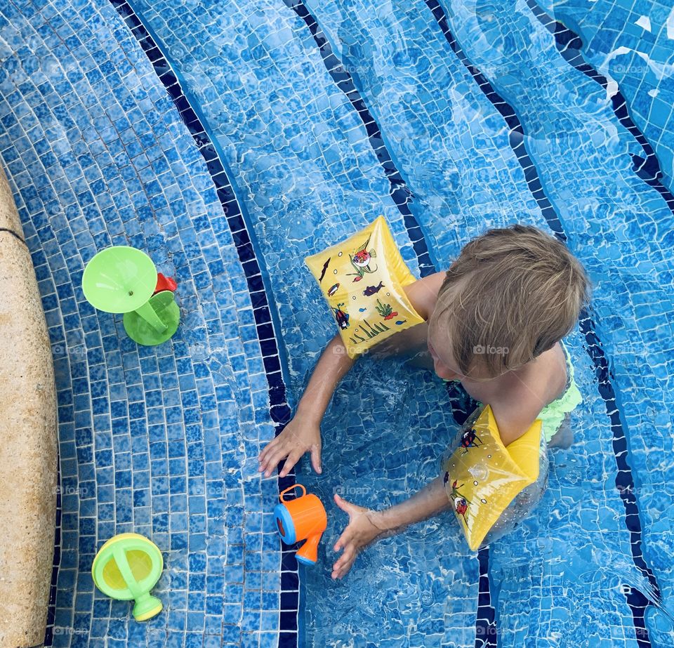 Little boy in pool with colorful toys 
