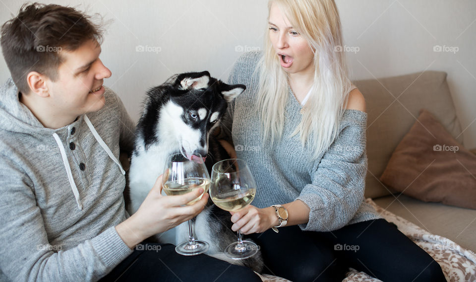 Young family couple and hushy dog drinking wine at home