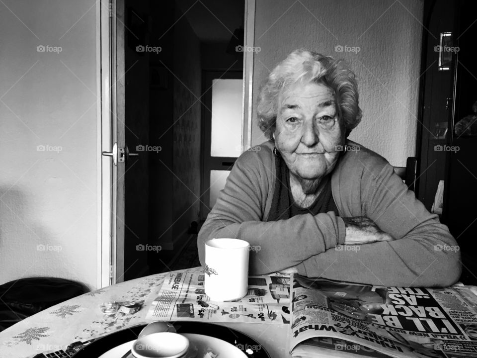 Old woman with news paper and coffee on table