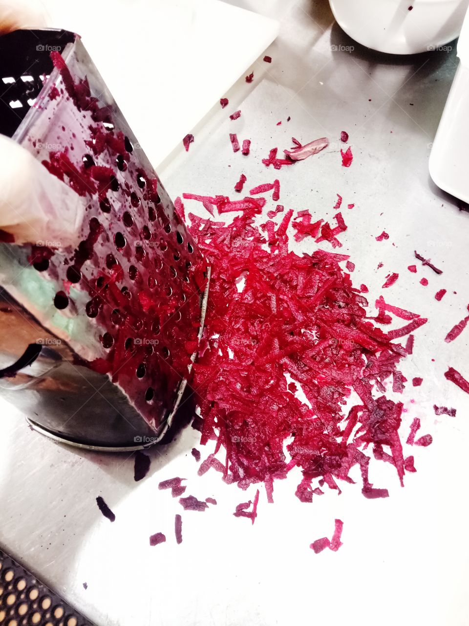 Grating fresh Beetroot for morning preparation in a commercial kitchen