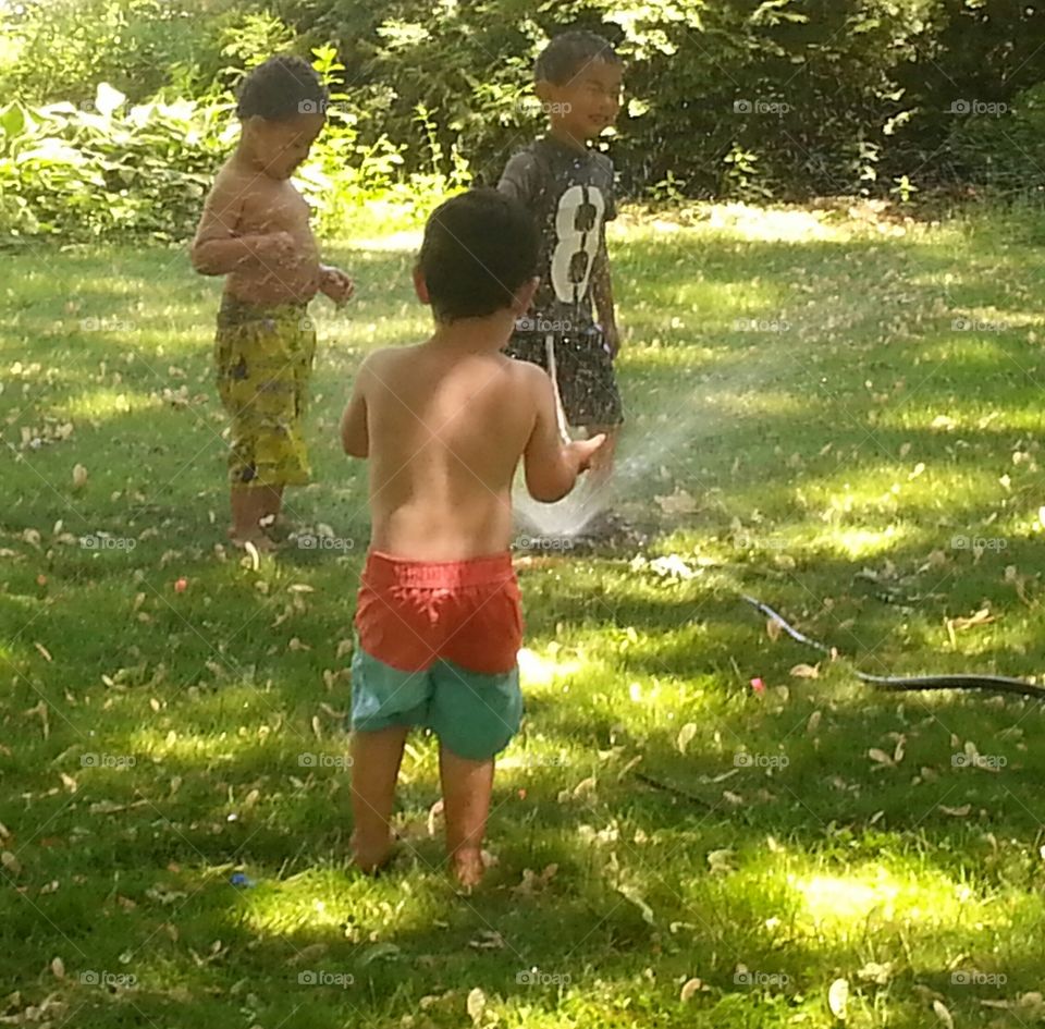 Cooling Off. Boys playing with sprinkler