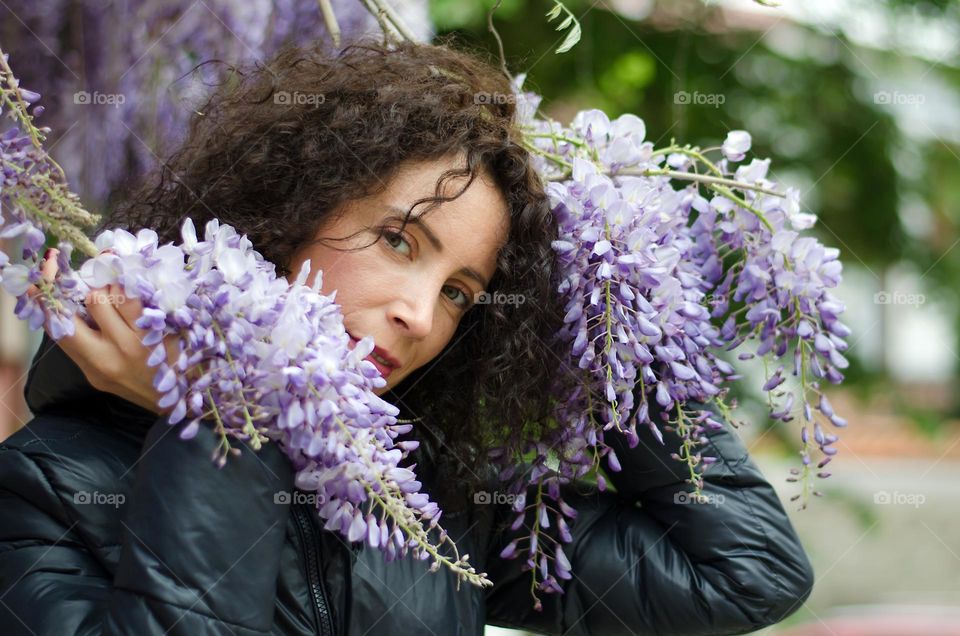 Portrait of a woman brunette with beautiful natural hair on background of Wisteria