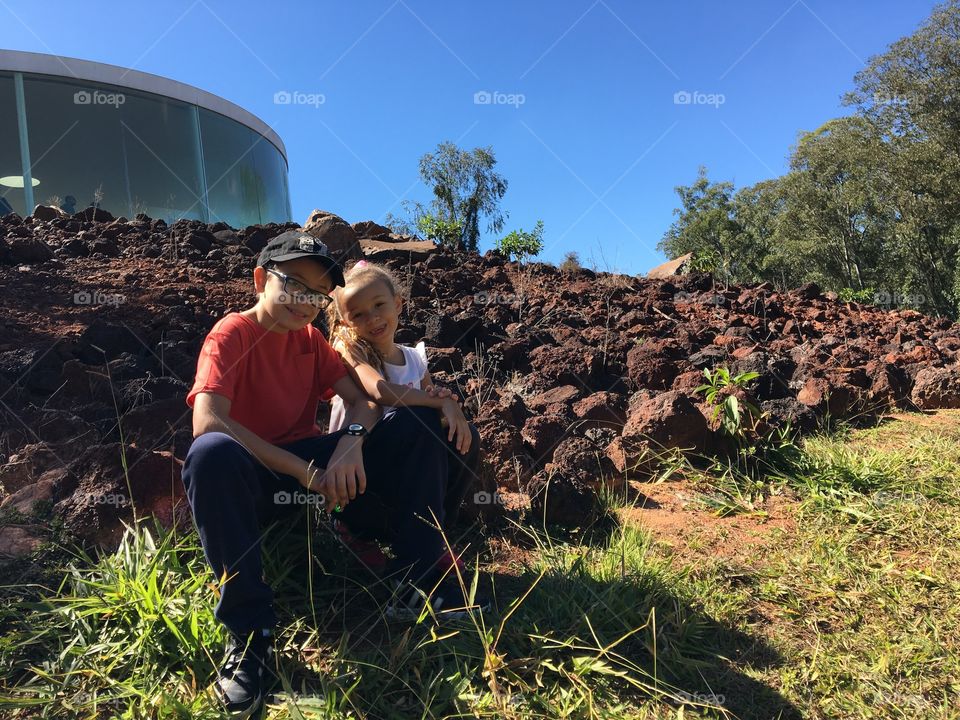 Brother and sister sitting on rock