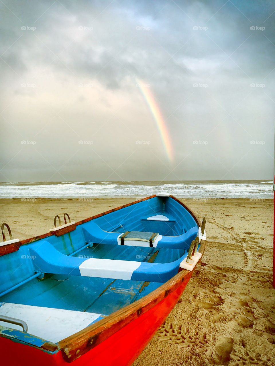 Boat on a rainy beach with a rainbow