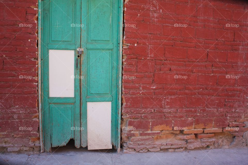 A colorful image of a red wall and  a worn green and white lucked door in San Miguel de Allende, Mexico 