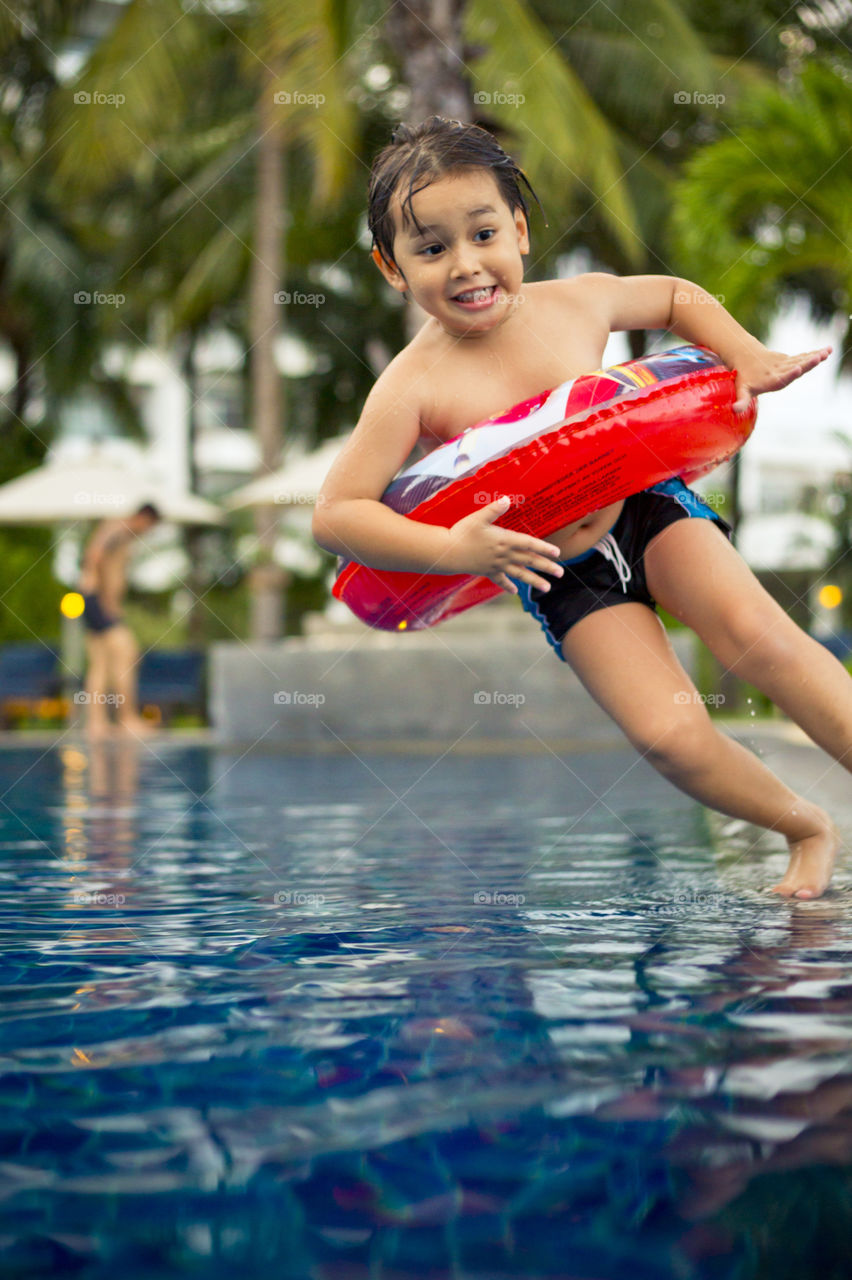 Happy kid falling into the pool. Thithi having fun