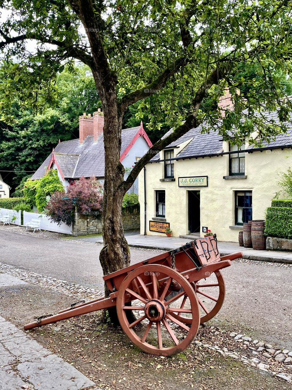 A red painted wagon sits in the foreground on the village street of a bygone era at Bunratty Folk Park.