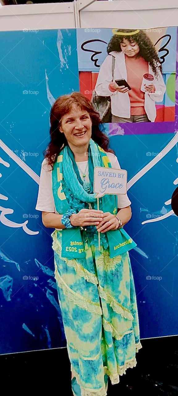 This nice smiling lady at the „Evangelical Church Day“ in „Nürnberg“, Germany was indeed saved by grace. The painted wings on the wall behind her are to indicate that her spirit lifts her up just like the wings of an angel. 2023. Hypnotic Productions