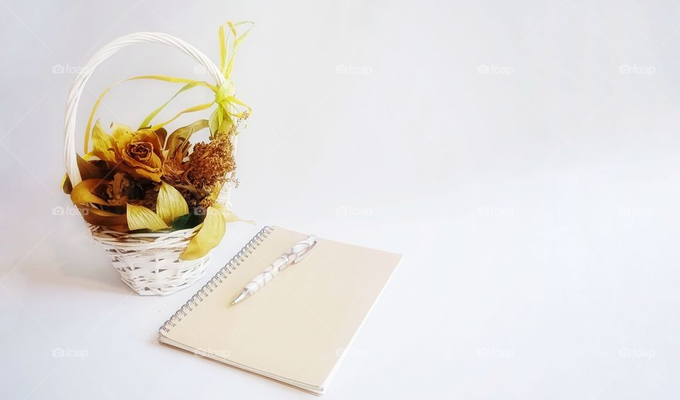 white background with notebook, pen and dries flower