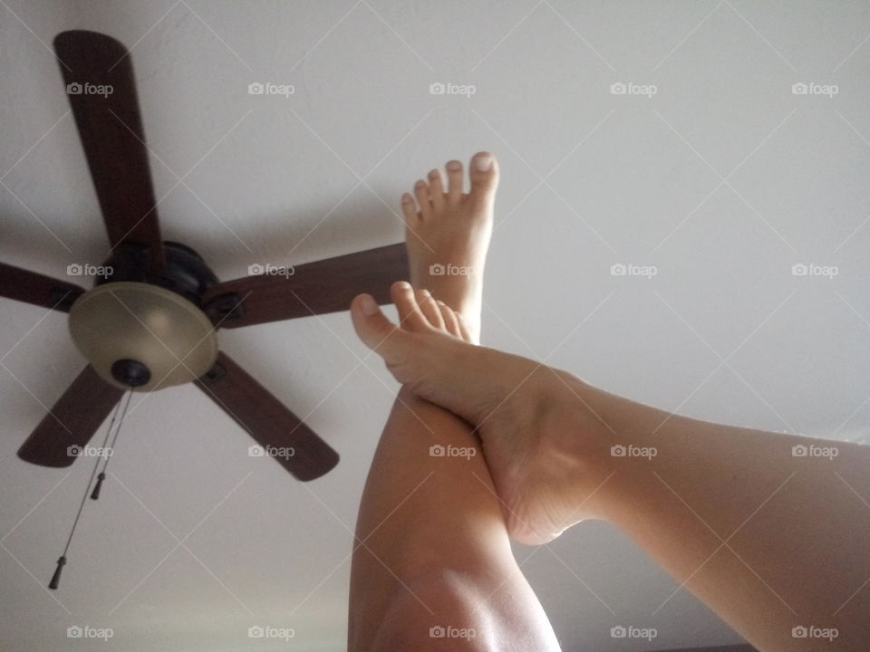 a womans foot rubbing against the other leg with her legs pointing towards the ceiling.