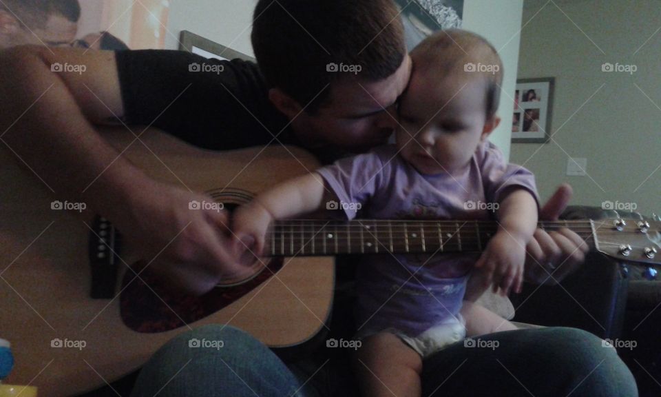 guitar playing baby. strumming strings with her daddy