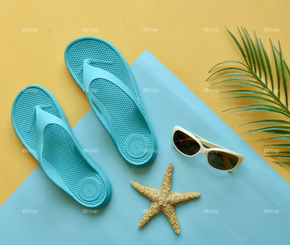 Flat lay still life flip flops,starfish, sunglasses, palm branch summer theme 