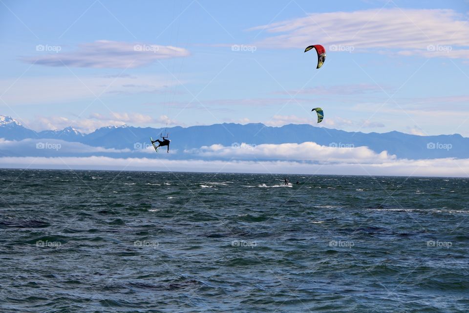 High winds perfect for windsurfing  , green and red kites , people trying to control them while riding and one jump high above .. what a fun to watch them !