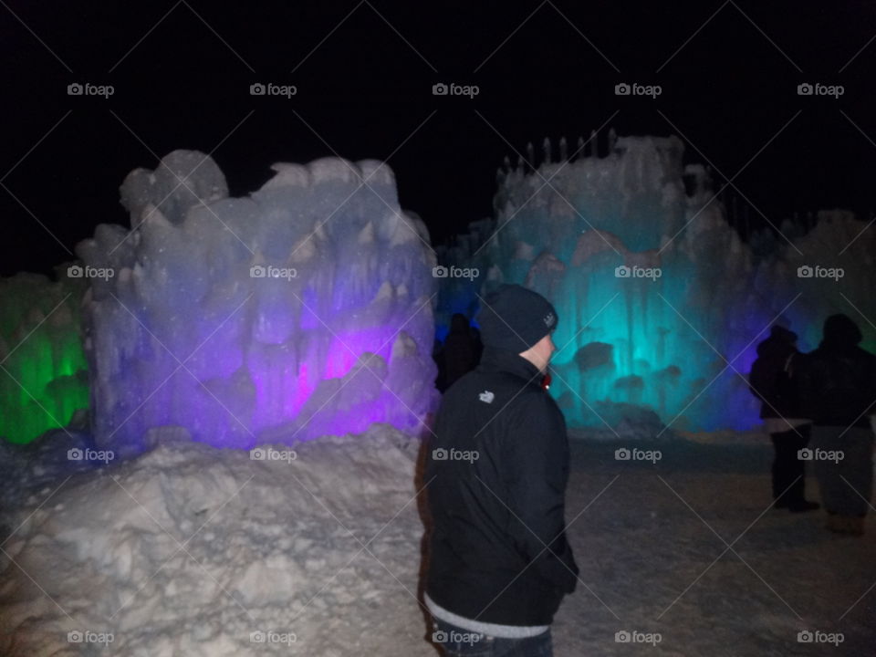 A man walking through the colorful ice castles of Lincoln, New Hampshire.