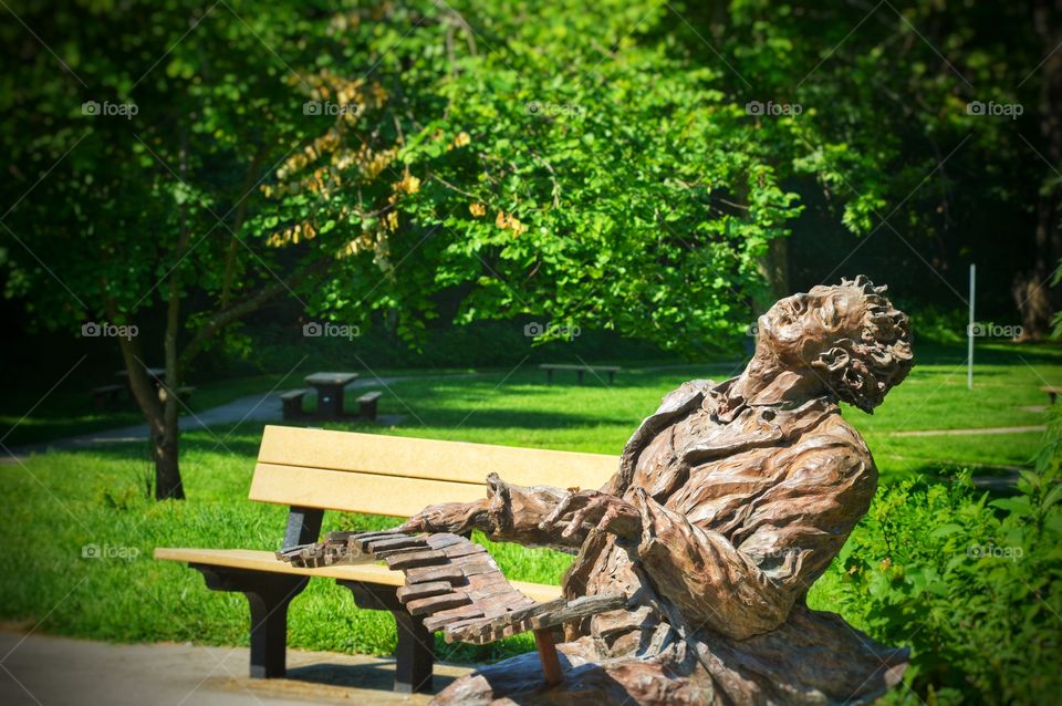 Historical statue in a Missouri park portraying musician Blind Boone on a piano.