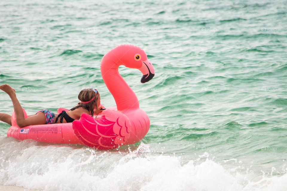 A girl floating on a flamingo in the ocean