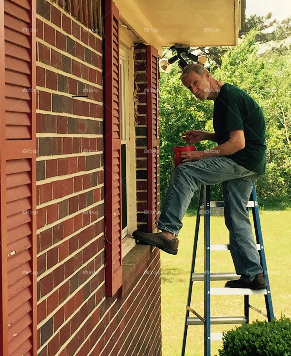 Senior man standing on ladder