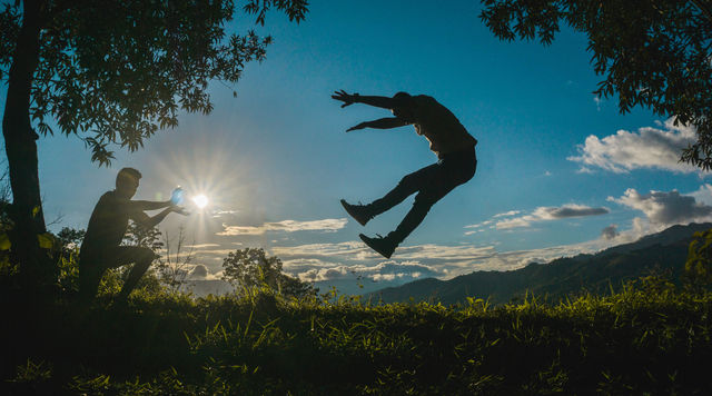 Composition of the silhouette of two guys imitating a kamehameha with the sunset