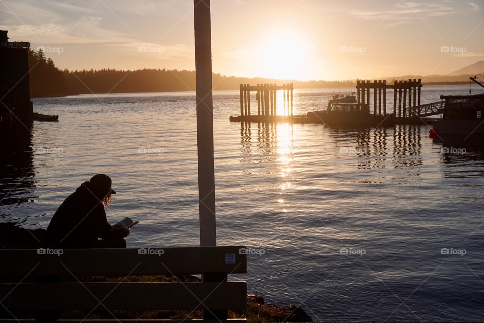 Silhouette of a guy reading a book on the shore ... love how the curls in his hair light up from the setting sun 