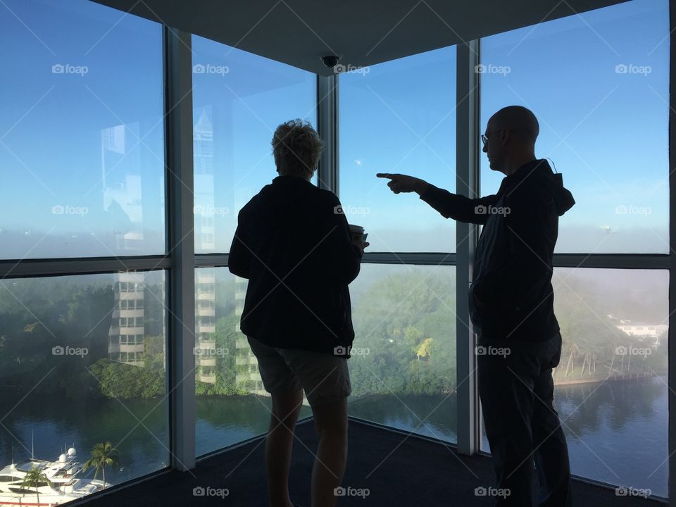 Man and woman standing by panoramic window of building, Miami Beach, Florida