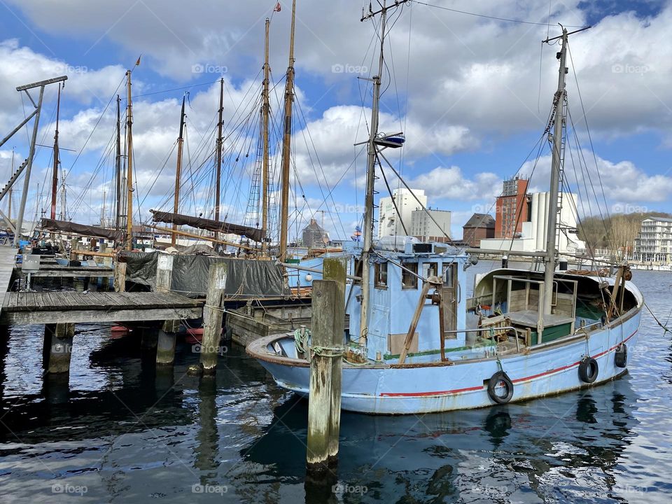 Kleines Fischerboot im Hafen. Leicht bewölkter Himmel, dunkles Wasser
