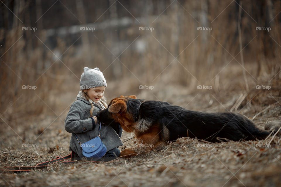 Little girl with German shepherd young male dog walking outdoor at spring day