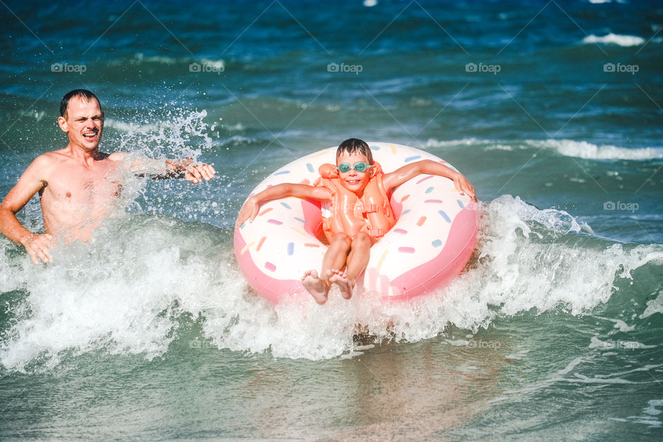 Father and son are frolicking on the waves