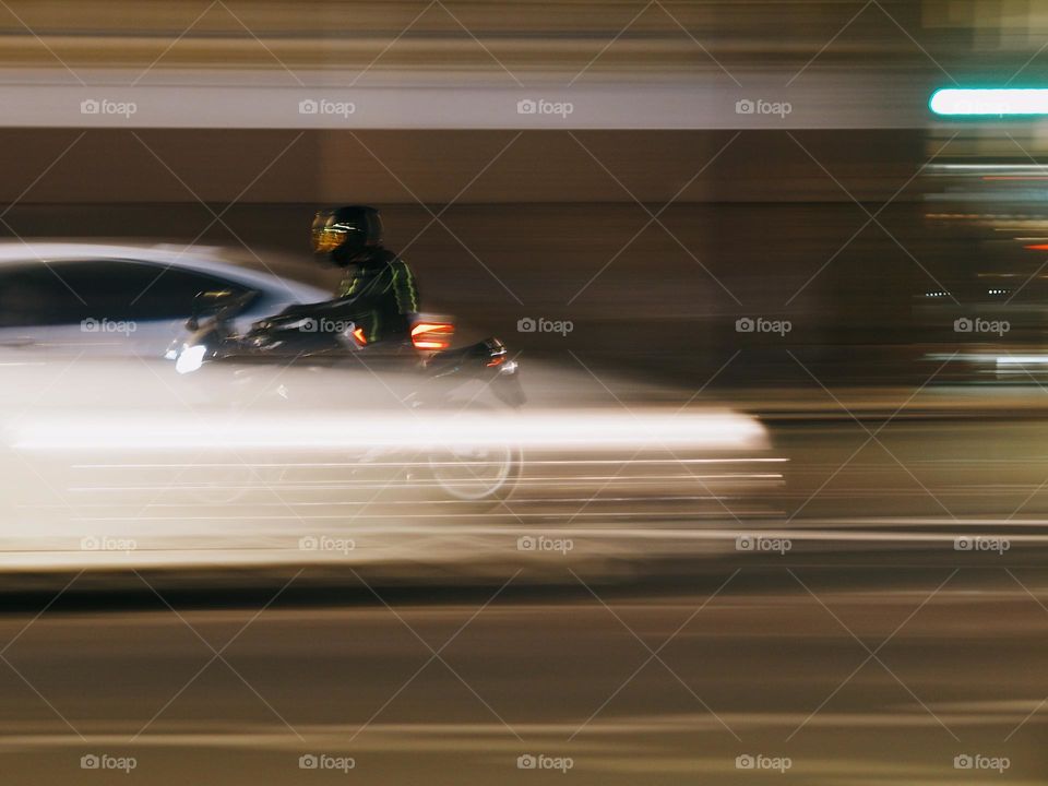 Motorcyclist with motorcycle in the night, long exposure 
