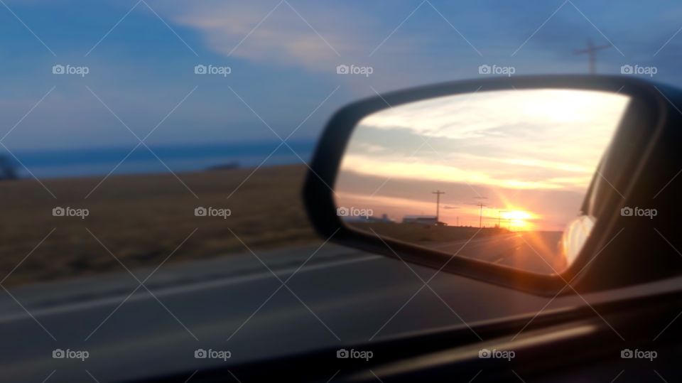 Sunset in Iowa taken in the side view mirror of a car. Mild tilt-shift applied to focus on the sun in the mirror