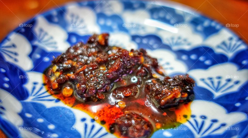 Chilli paste in an ornate blue saucer. Image features shallow depth of field with vibrant colors.