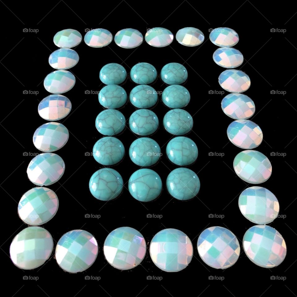 Two rectangles, one within the other, made with two different kinds of round beads. 