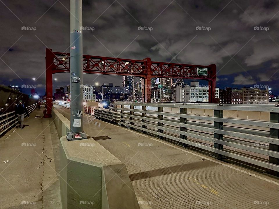 This is the “Pulaski Bridge” at “Newtown Creek” that connects “Greenpoint”, Brooklyn to LIC, Queens seen from the pedestrian lane. The bicycle lane is sectioned off from the car lane by use of a metal railing. 2023. Hypnotic Productions