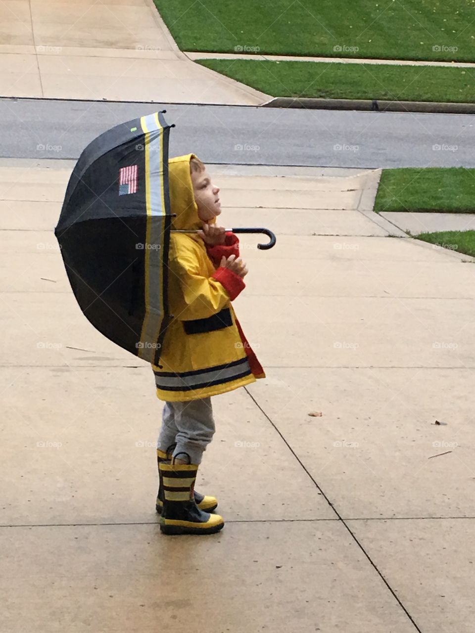Little boy standing on the park and holding umbrella