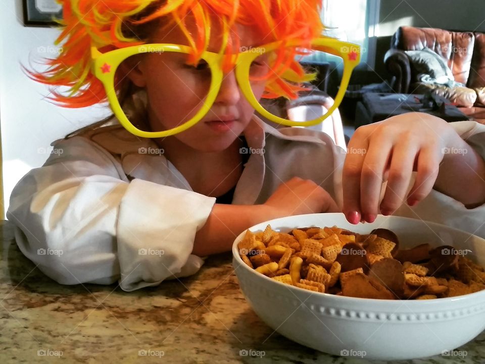girl with wig eating pretzel snack mix